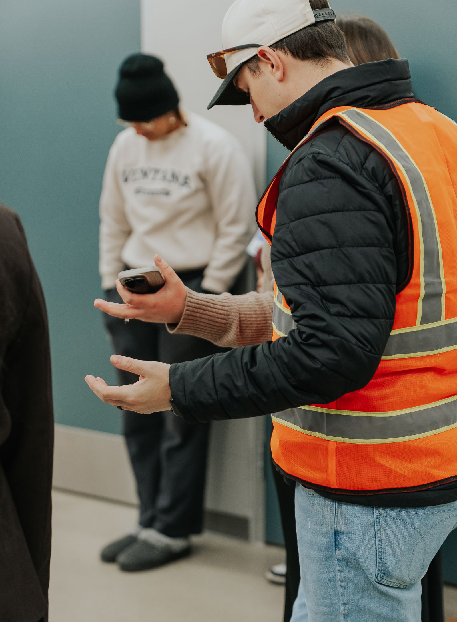 A Dream Team volunteer in an orange vest greeting guests at the entrance